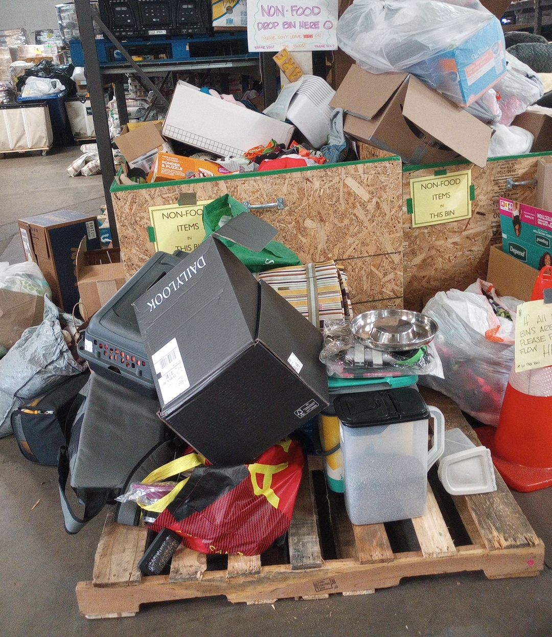 Donation bins in a warehouse, piled high with bags, boxes and pet supplies.